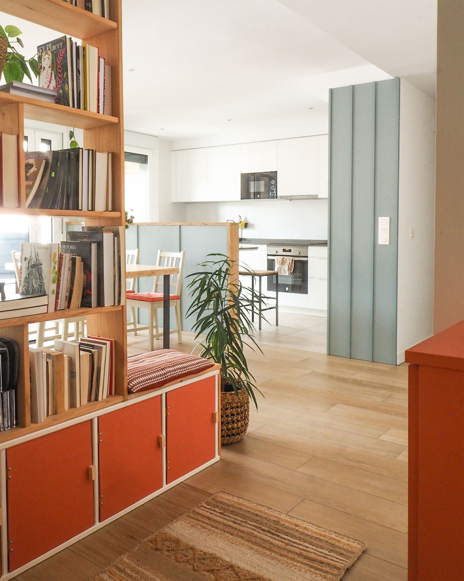 Reforma de vivienda juvenil, luminosa y colorida con estanterias de madera en la entrada