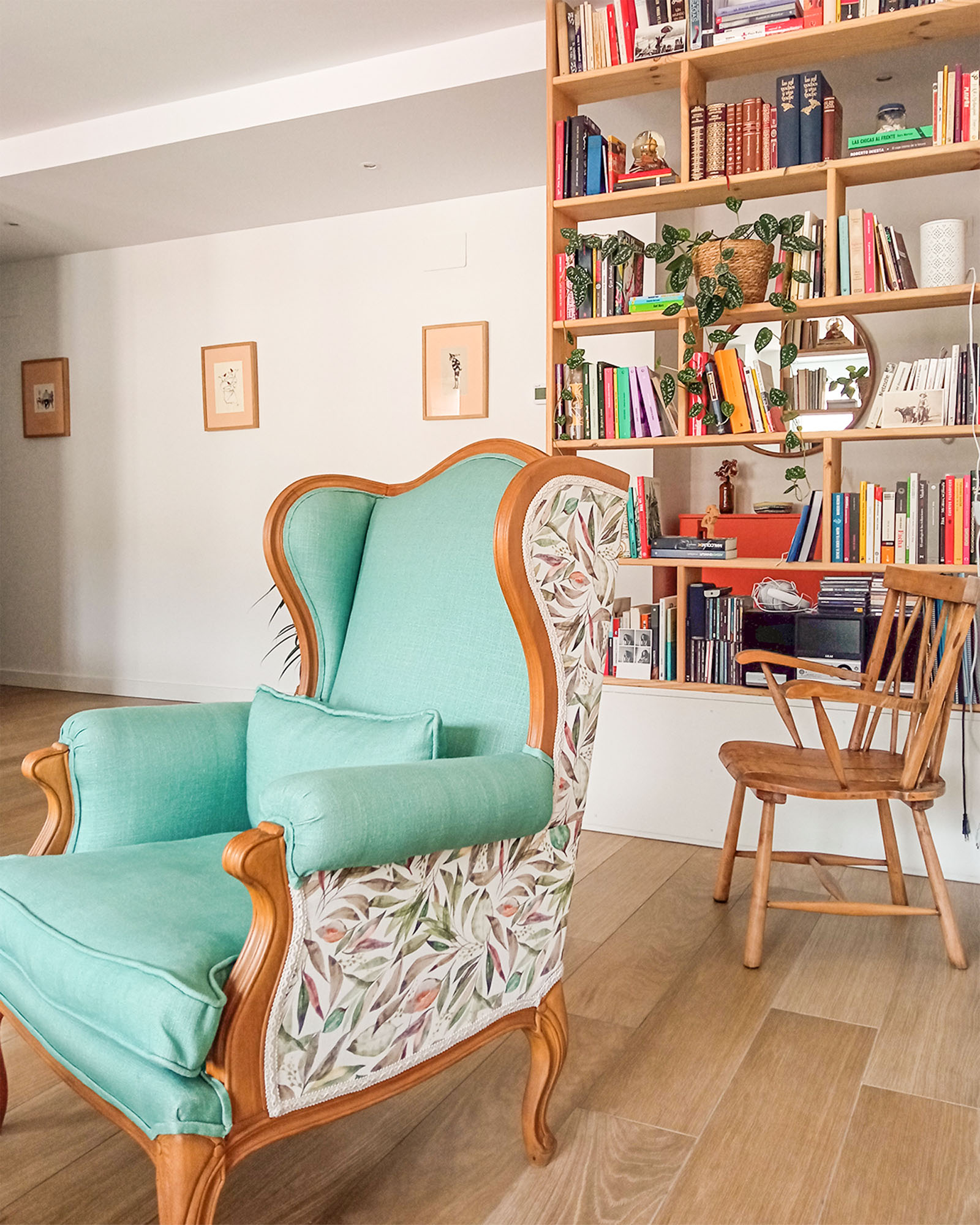 Reforma de vivienda juvenil, luminosa y colorida con sillón colorido y estanterias de madera